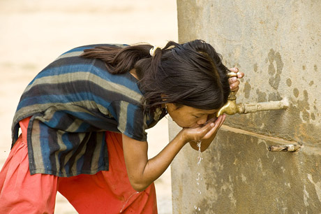 A girl drinking water from a tap that leads to a local spring. Through WWF funding (Under the TAL joint government and WWF proje: A girl drinking water from a tap that leads to a local spring. Through WWF funding (Under the TAL joint government and WWF project) and help from the local community (Community Forest Co-ordination Committee), many springs have been found in the area and are now set up to provide water to the local populace. Due to deforestation and soil erosion springs are vital in providing people with fresh, clean water. With more springs being used and trees being planted it is hoped that water levels will begin to rise once again. Lamahai, western Terai, Nepal. Photograph © Simon de TREY-WHITE / WWF-UK